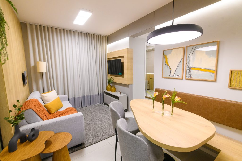 Sala de estar e jantar integradas com decoração moderna em tons neutros e detalhes em amarelo mostarda e laranja queimado. Imagem ilustrativa para post sobre tendências de decoração para o outono 2025, do blog da Morar Construtora.